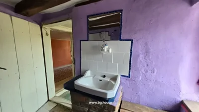 Bathroom sink on brick base with mirror, purple walls, and white door.