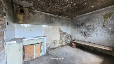 Room showing a tiled wall section, peeling paint, exposed brick, and a wooden bench supported by a log.