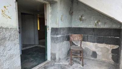 Room corner featuring a wooden chair and walls painted with a two-tone pattern and floral designs.