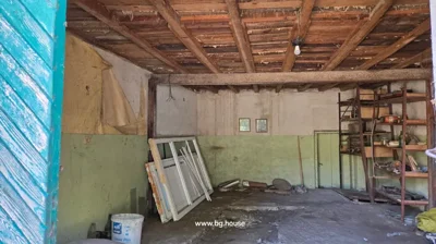 Room with exposed wooden ceiling beams, partially plastered walls, and scattered construction materials