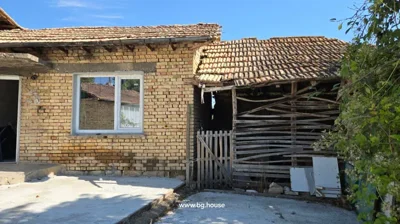 Brick house with white-framed window and adjacent wooden structure with slatted walls and a small gate.