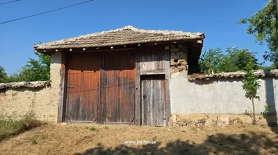 Detailed view of the wooden gate within the stone and plaster wall, topped with a tiled roof.