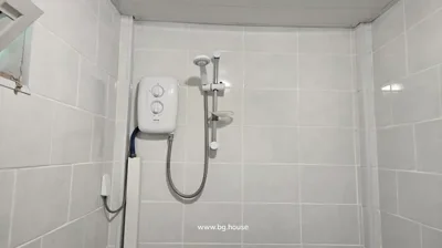 White shower head mounted on wall with adjustable holder, water heater unit, and tiled walls