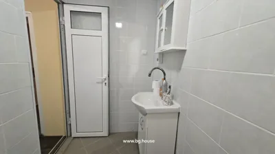 White bathroom sink with faucet, mirror cabinet above, and white door leading out of bathroom