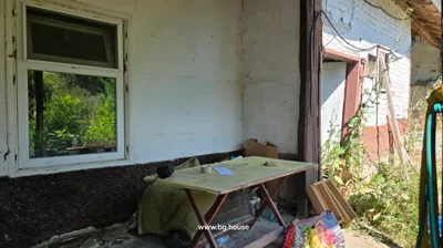 Porch area showing window, table with items on it, and plants growing nearby