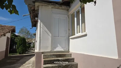 White exterior door accessed by three concrete steps, part of a white building with a pathway alongside.