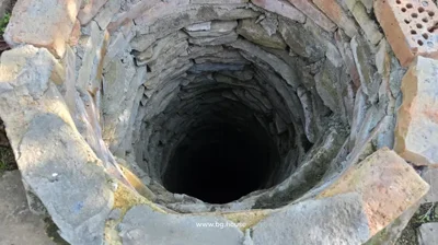 Close-up view looking down into a deep, circular stone-lined well.