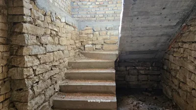 Stone walls and concrete stairs inside a building under construction with sunlight coming from above