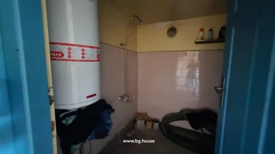 Bathroom interior featuring a showerhead, a large water heater, and miscellaneous items stored in the space.