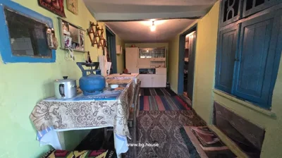 Room interior with yellow walls, blue doors and cabinets, table with tablecloth, kitchen utensils, and carpet.