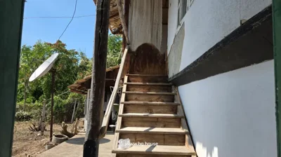 Wooden stairs with handrail leading to an upper floor door of a traditional house with white walls