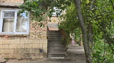 Concrete stairs leading to upper floor of brick house, with trees and a person standing near the stairs.