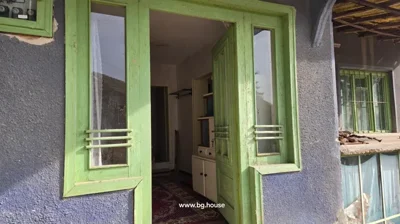 Green wooden door with glass panels partially open, showing interior hallway with white walls and carpet on floor