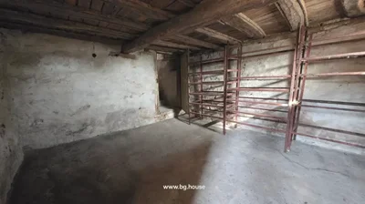 Room with concrete floor, wooden ceiling beams, metal shelving units, and open doorway